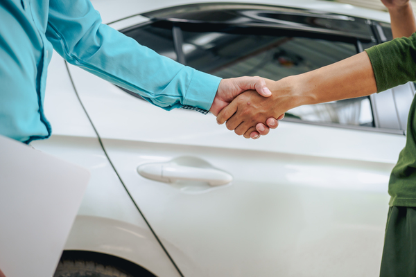 Used car buyer and private seller shaking hands completing vehicle purchase deal